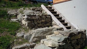 Eine Steintreppe führt zu einem Holzhaus.