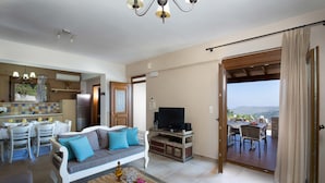 Un amplio espacio habitable con sofá, televisión, mesa de comedor y un balcón con mesa y sillas.
