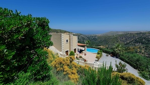 Una villa con piscina, rodeada de exuberante vegetación y colinas.
