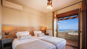 Habitación doble con una cama y cabecera de madera, una mesita de noche con lámpara y vistas al mar a través de un ventanal.