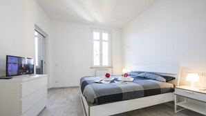 A modern bedroom with a bed, bedside table, and a TV on a dresser.