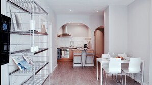 Une cuisine moderne avec des meubles blancs, une cuisinière et un coin repas comprenant des chaises et une table, le tout dans des tons blancs.