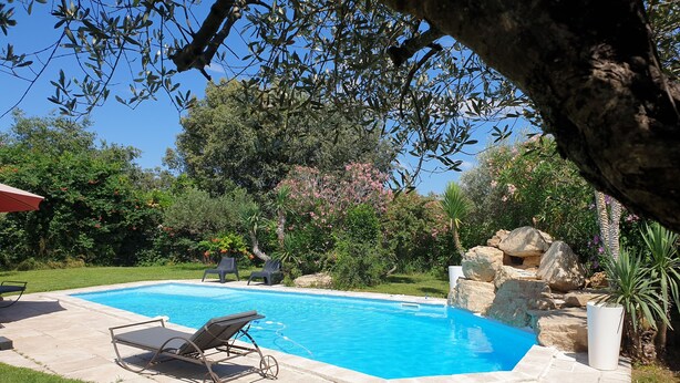 A swimming pool with lounge chairs and a rock feature, surrounded by greenery and trees. - Upscale villa near UZES, private swimming pool, enclosed grounds, Wifi. (Collias)