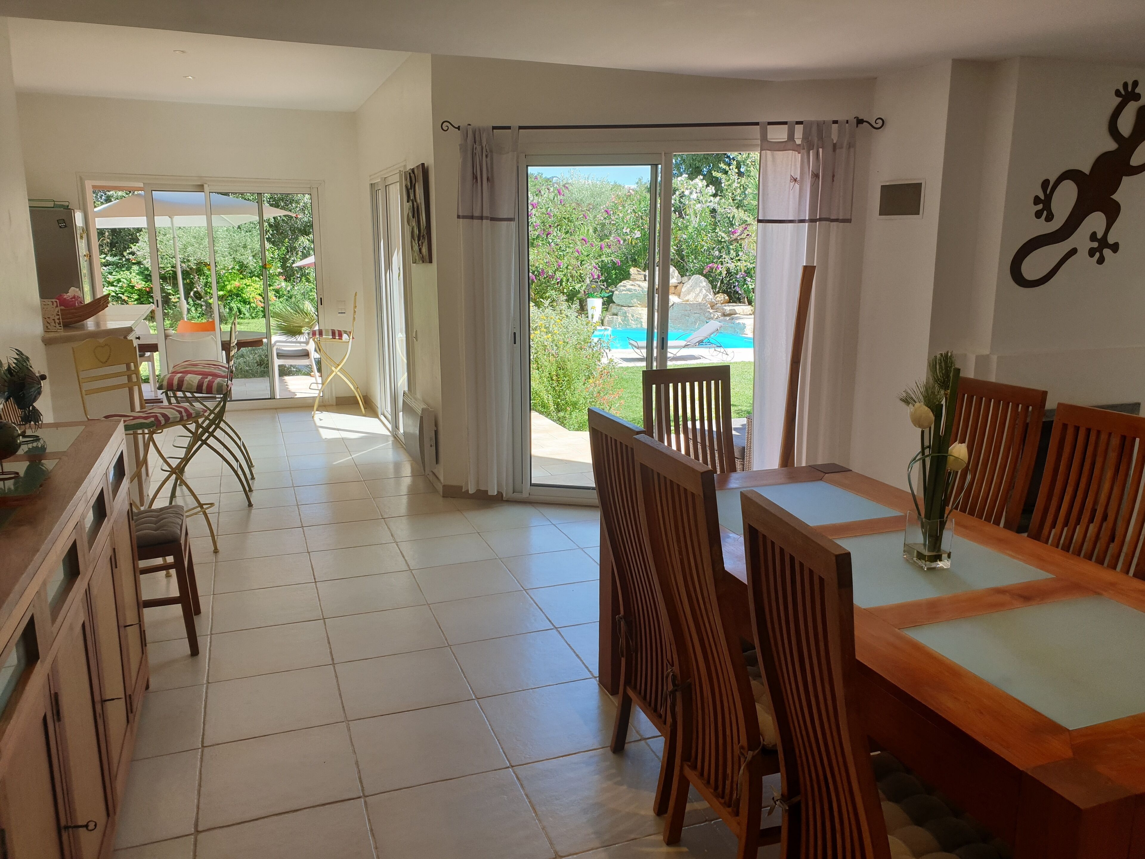 Une salle à manger spacieuse, dotée de meubles en bois et offrant une vue sur une piscine et un jardin.