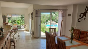 A spacious dining area with wooden furniture and a view of a swimming pool and garden. - Upscale villa near UZES, private swimming pool, enclosed grounds, Wifi. (Collias)