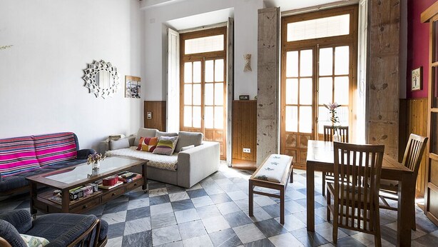 Una sala de estar con sofá, mesa de centro y comedor con mesa y sillas.
