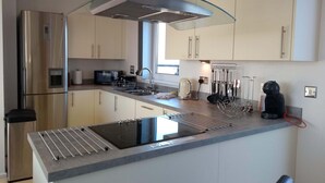 A modern kitchen with a stainless steel refrigerator, a built-in microwave, a kettle, and a coffee maker. - 5* Self Catering Penthouse, Llanelli, Beach, Sea Views, Walks, Golf, Cycle. (Llanelli)