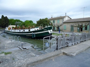 A narrow canal with a green boat docked at a lock.
