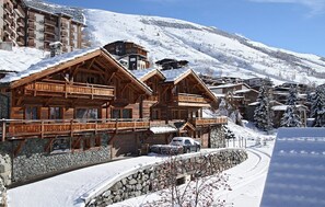 A wooden chalet-style building with balconies, surrounded by snow-covered mountains and a clear sky. - Chalet cosy avec piscine privée | Près des pistes (Les Deux Alpes)