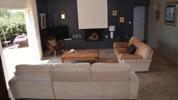 Un salon avec un canapé beige, une table basse en bois et un téléviseur.