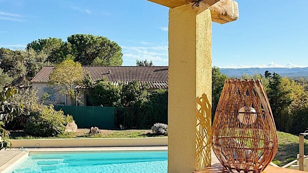 Un espace aménagé au bord de la piscine, avec une pergola en bois, un grand saladier en verre et un évier en métal.