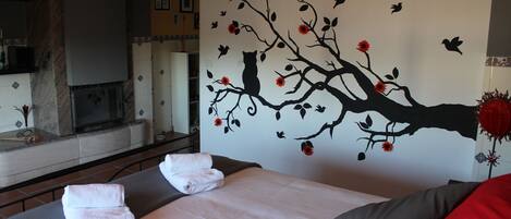 Un dormitorio con cama, toallas, chimenea y un mural en la pared.