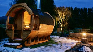 Een houten hut met een gebogen dak, een schoorsteen en een verlicht interieur.