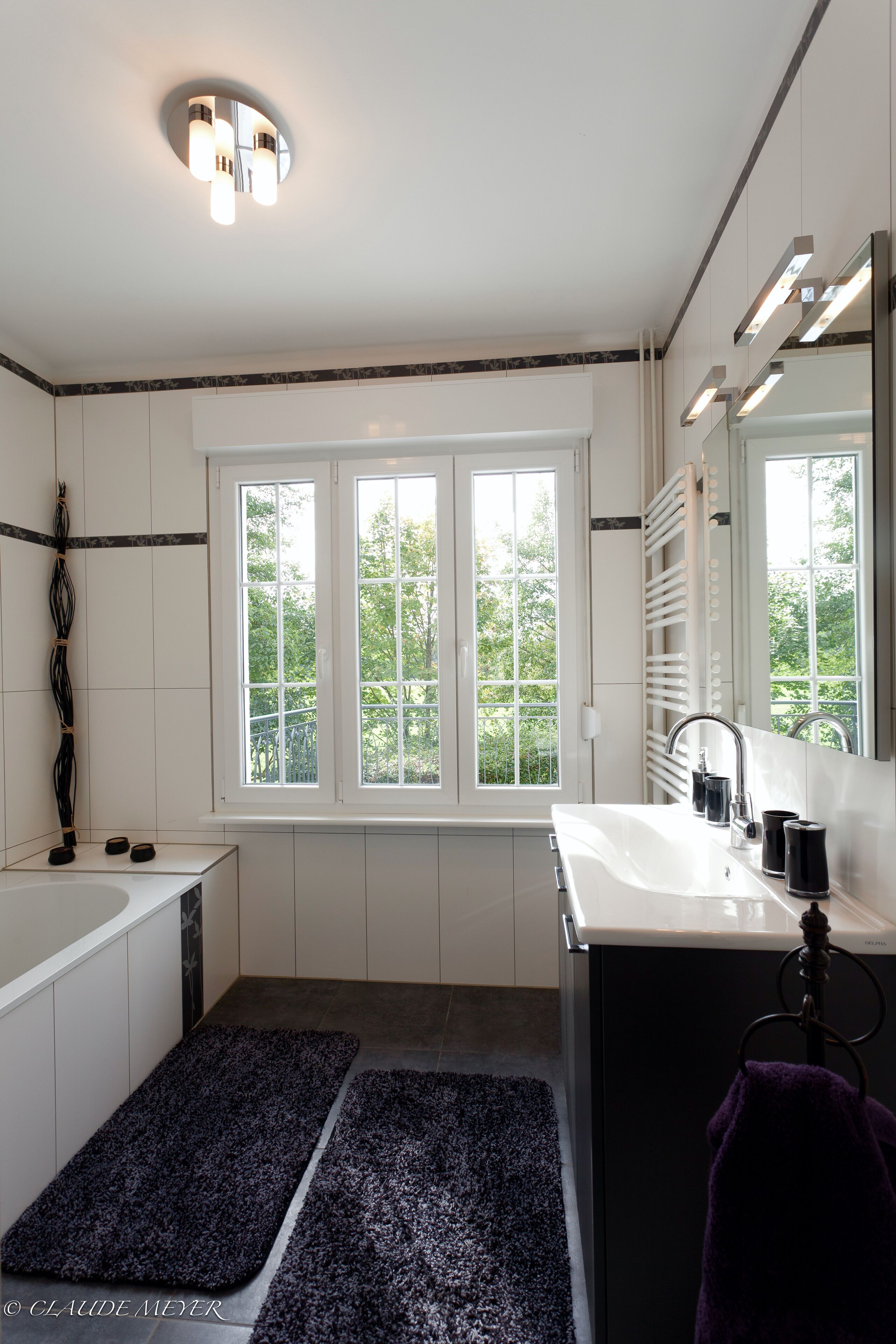 Un baño moderno con una bañera, un lavabo y un ventanal grande.
