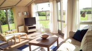 A living room with a TV, sofa, chairs, and a table. - Bright Danish wooden house with unobstructed views of the countryside, pets welcome (Kating)