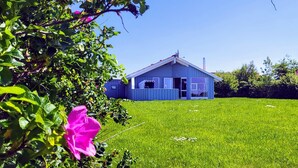 A house with a blue exterior, a visible garage door, and a well-maintained lawn. - Bright Danish wooden house with unobstructed views of the countryside, pets welcome (Kating)