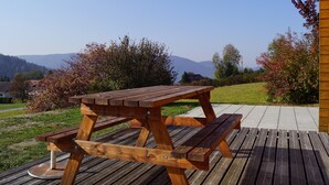 Et træborde til picnic på en træterrasse med bjergudsigt i baggrunden.