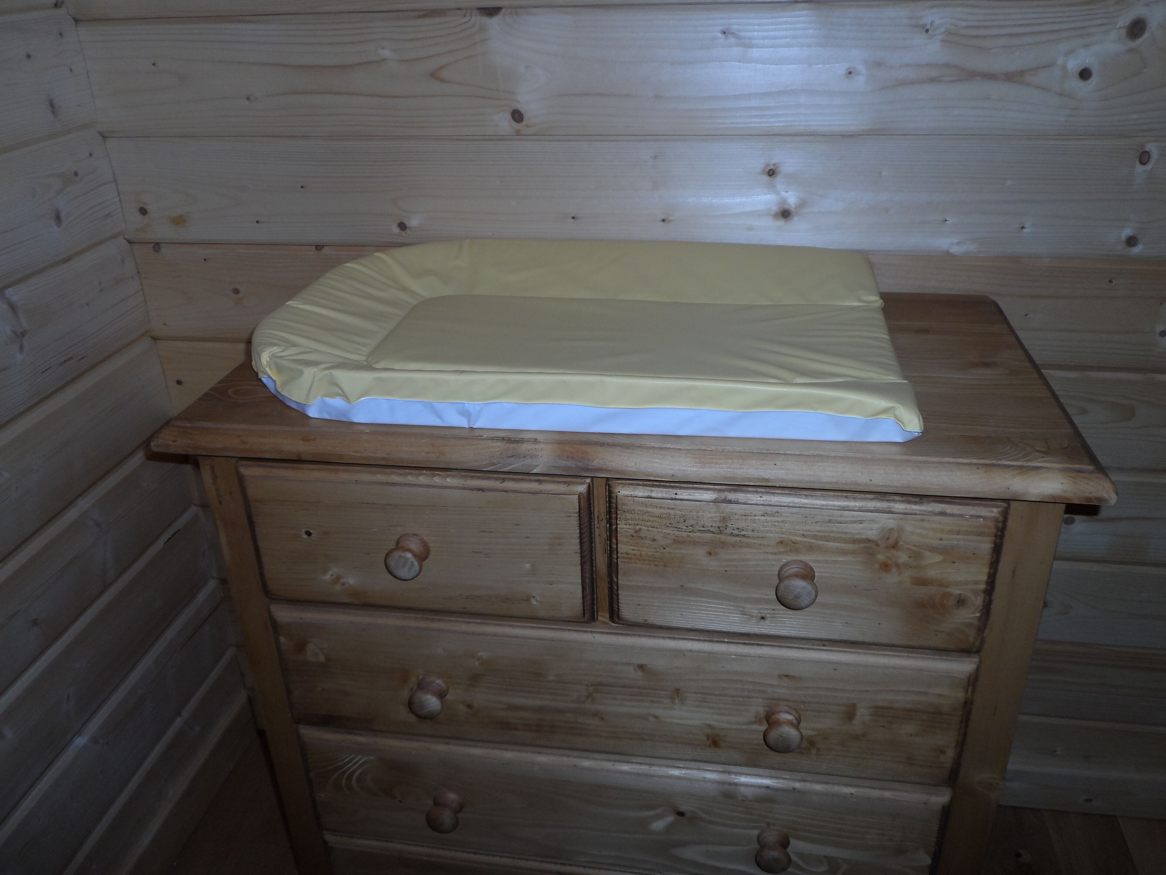 A wooden dresser with a mattress on top.