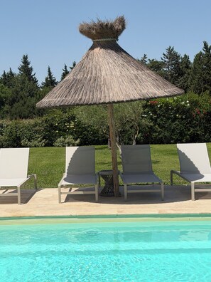 A poolside area with a thatched umbrella, lounge chairs, and a clear pool. - Villa 220m2, land 3000m2, 5 "village on foot, 4km Saint-Rémy-de-Provence (Eyragues)