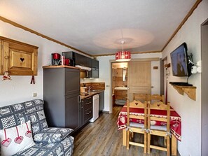 A compact living space with a kitchenette, a dining area, and a sofa with patterned cushions.