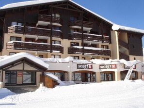 A multi-story ski resort building with balconies and a ski lift visible. - Ski-in/ski-out: 2 rooms, 5 ppl, terrace, free parking, WiFi (Les Menuires)