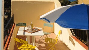 A terrace with a table, chairs, and an umbrella.