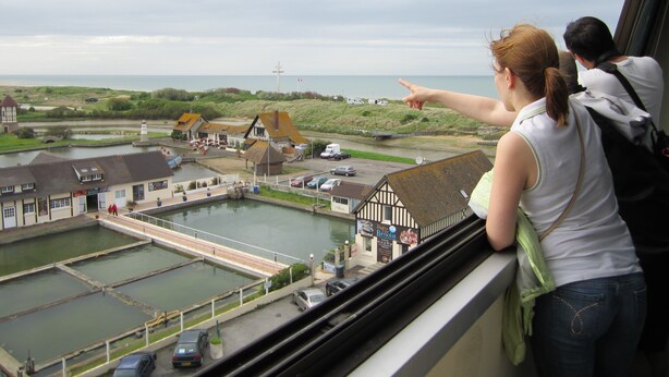 Une ville côtière dotée de bâtiments traditionnels, d’un port de plaisance et offrant une vue sur la mer.
