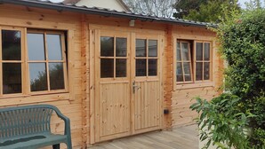 A wooden cabin with large windows and a bench outside. - quiet comfort cottage, sea view, terraces and heated indoor pool (Ver-Sur-Mer)