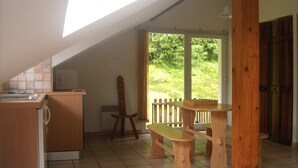 Une cuisine avec un banc en bois, une petite table et une vue sur la verdure à l’extérieur.