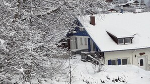 Une maison recouverte de neige, avec un porche avant bien visible et une cheminée.