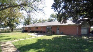 A single-story brick house with a covered porch, a front yard, and a driveway. - Classic Family Ranch -- Experience Real Texas Country (Montalba)