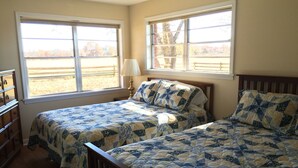 A bedroom with two beds, a dresser, and large windows with a view of trees and a fence. - Classic Family Ranch -- Experience Real Texas Country (Montalba)