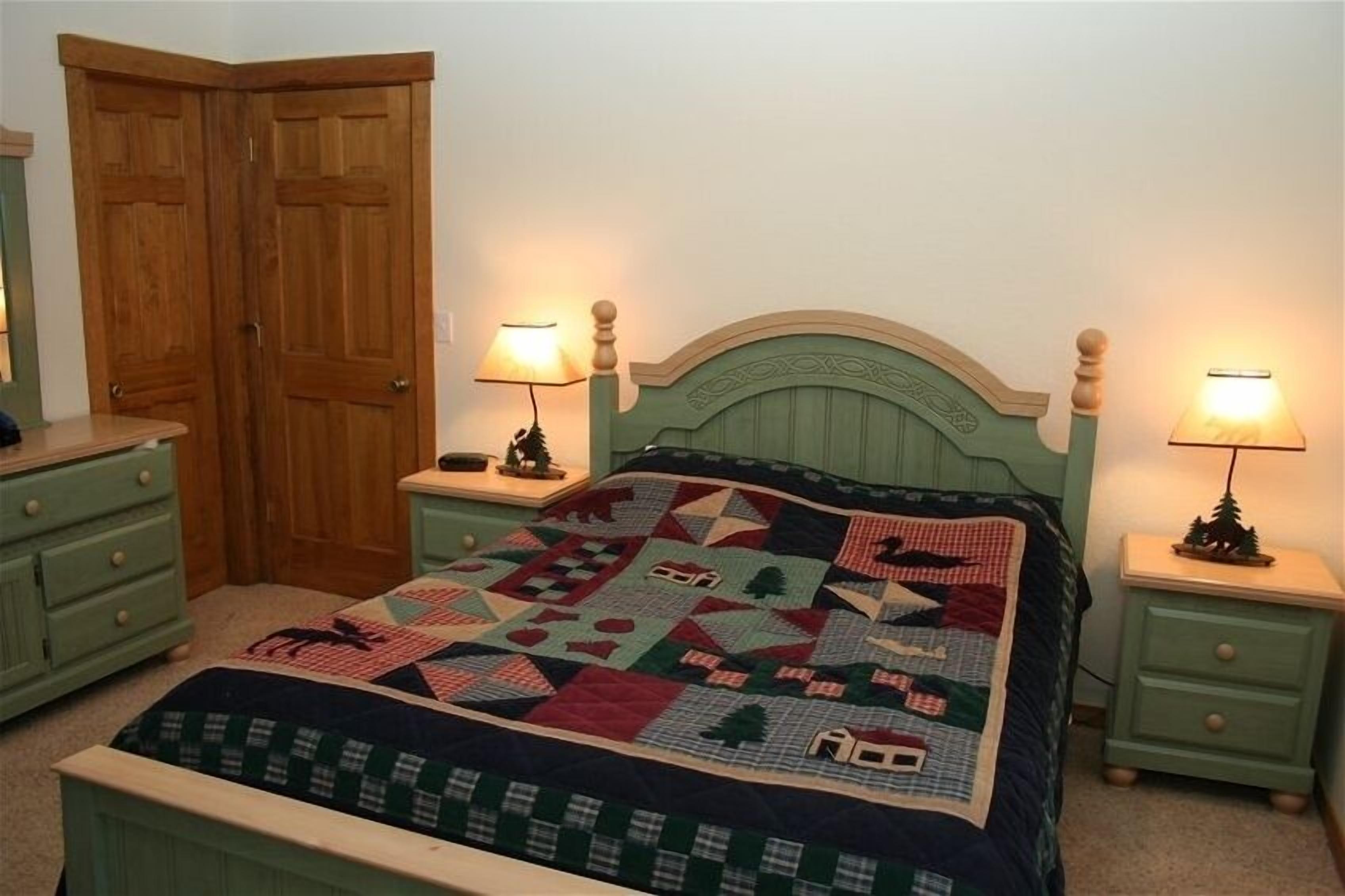 A bedroom with a bed, two nightstands, a dresser, and a wardrobe.