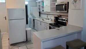 A compact kitchen with white cabinets, a microwave, a stove, and a sink.