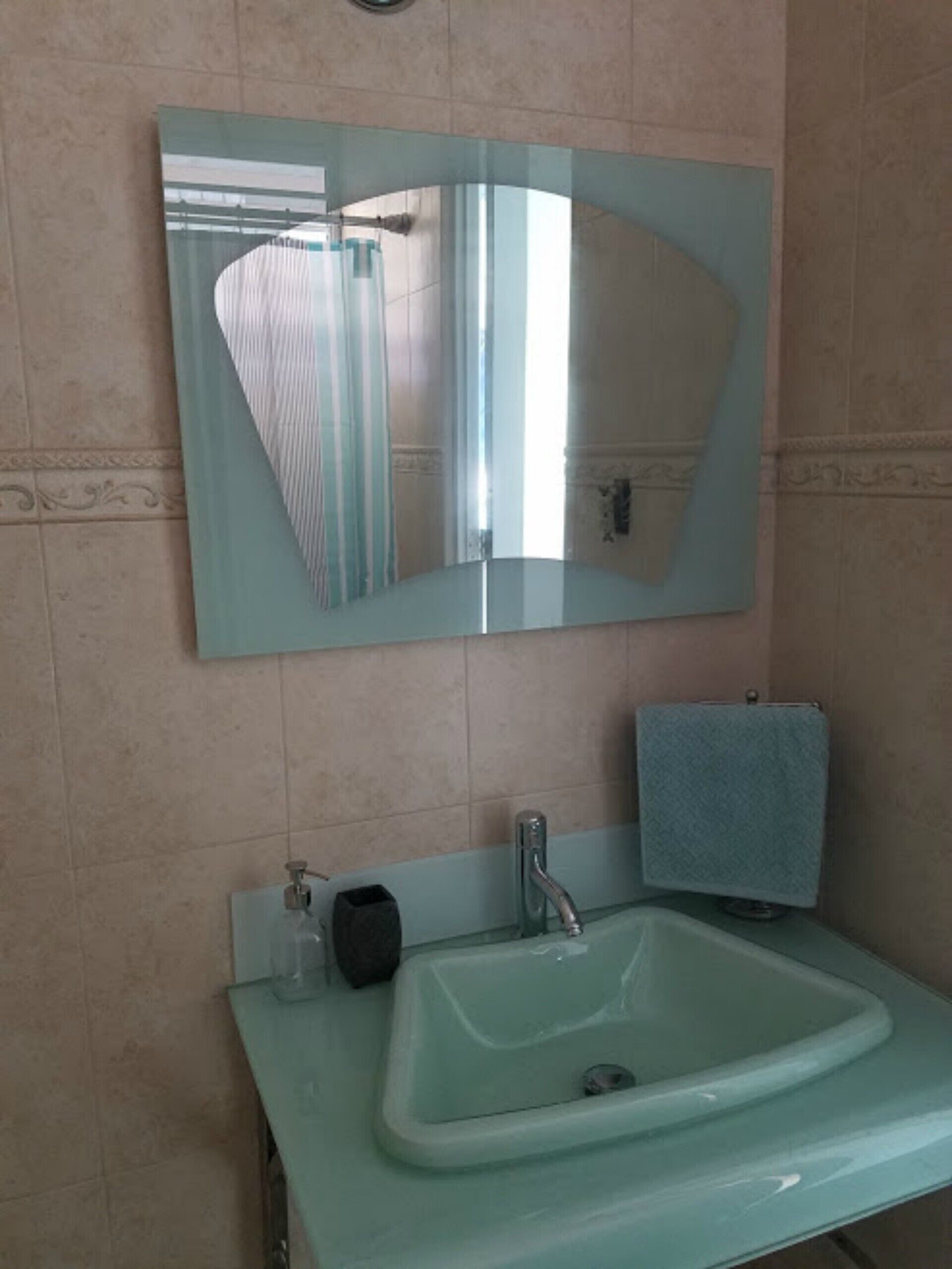 Une salle de bain avec un miroir rectangulaire, un lavabo et un porte-serviettes.