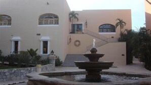 Un edificio con una fontana, una scalinata e palme.