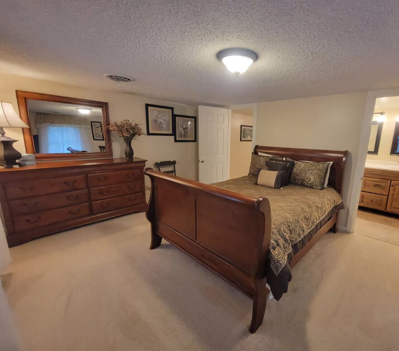 Un dormitorio con cama de madera, cómoda y espejo.
