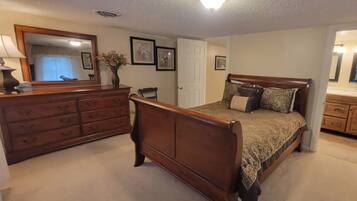 Un dormitorio con cama de madera, cómoda y espejo.