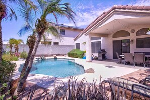 A swimming pool with a curved edge, surrounded by palm trees and a patio area with outdoor furniture. - The Whole Package with Heated Diving Pool !! (Glendale)
