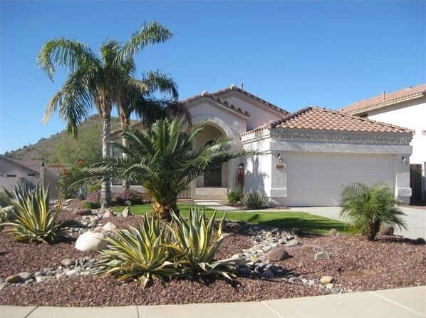 A residential house with a tiled roof, a stone facade, and a well-maintained garden with palm trees and agave plants. - The Whole Package with Heated Diving Pool !! (Glendale)