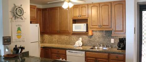 A kitchen with wooden cabinets, a microwave, a dishwasher, and a ceiling fan.