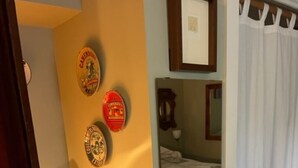 Une chambre à coucher avec un lit, une table de chevet sur laquelle se trouve un livre, et un miroir au mur.