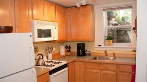 Une cuisine avec des meubles en bois, un réfrigérateur blanc, une cuisinière et un four à micro-ondes.