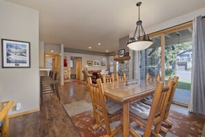 A dining area with a glass-top table, wooden chairs, and a chandelier.