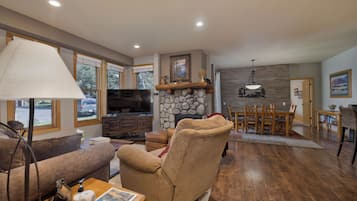 A living room with a fireplace, a television, and a dining area with wooden furniture.