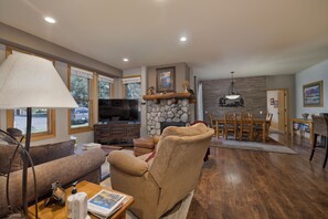 A living room with a fireplace, a television, and a dining area with wooden furniture.
