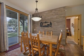 Un coin repas avec une table et des chaises en bois, un lustre et un élément décoratif fixé au mur.