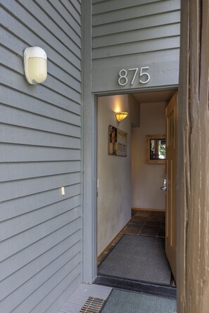 A house entrance with a number 875 sign, a welcome sign, and a door with a doormat.
