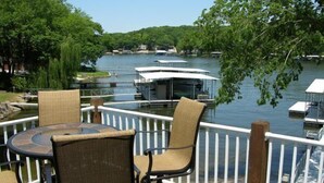 Une terrasse dotée de mobilier d’extérieur et offrant une vue sur un lac où naviguent des bateaux.