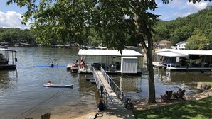 Une jetée au bord du lac avec des bateaux, un espace de repos couvert et une zone herbeuse avec des chaises.